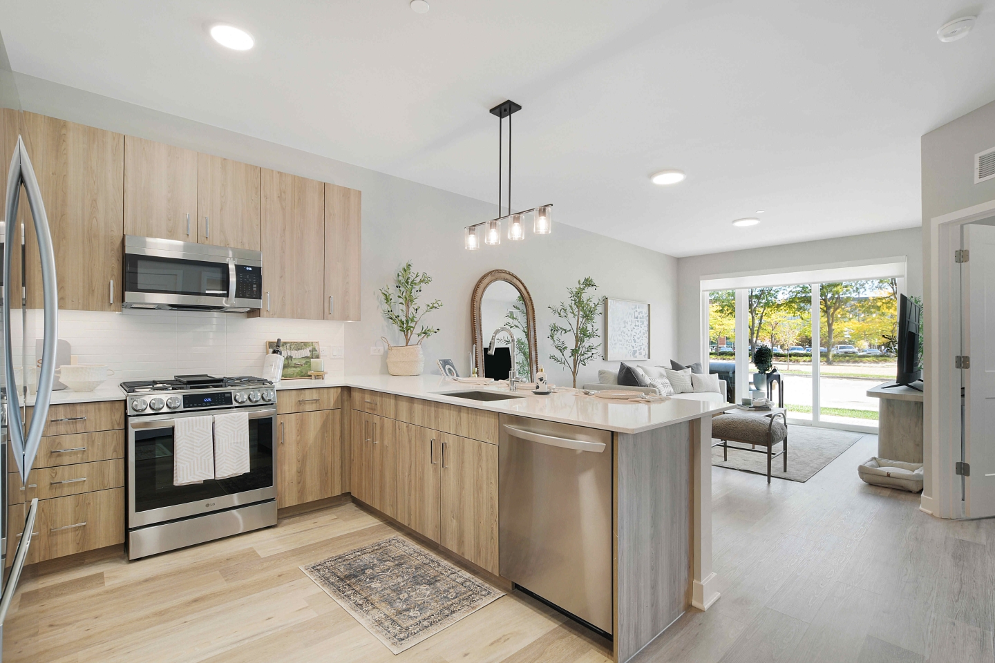 Luxury kitchen with hardwood floors with stainless steel appliances, pendant lighting, quartz counters, and a patio